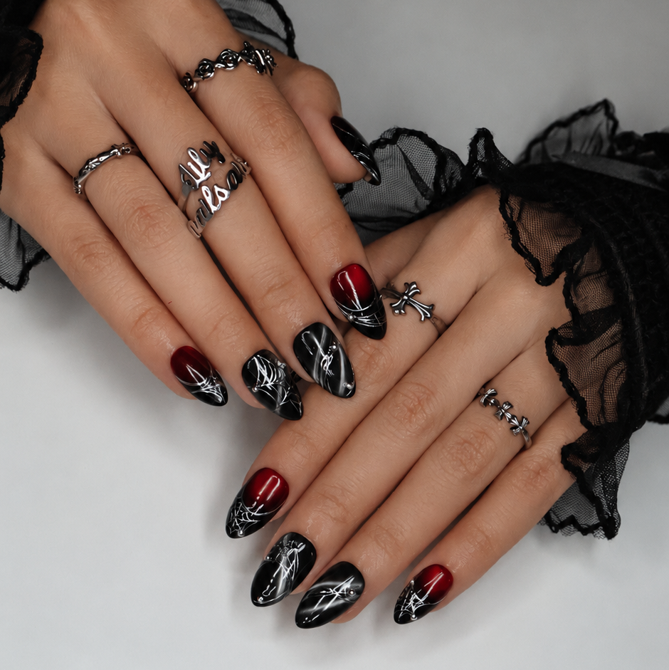 Arachne handmade gothic Halloween press-on nails — short almond set in blood-red and black cat-eye shimmer with silver spiderwebs and metallic bead accents.