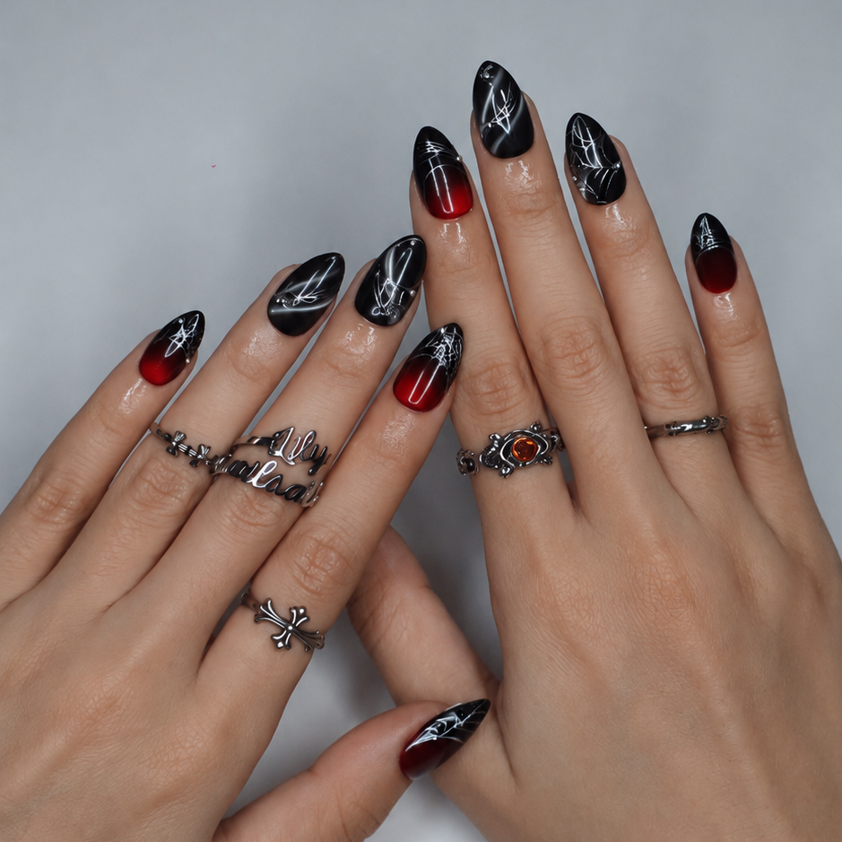 Arachne handmade gothic Halloween press-on nails — short almond set in blood-red and black cat-eye shimmer with silver spiderwebs and metallic bead accents.