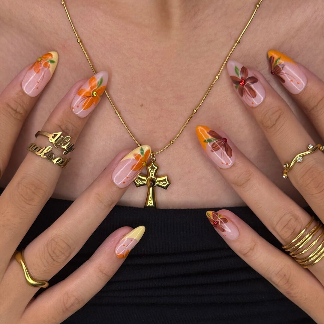 Autumn floral press on nails with hand-painted orange and red flowers, gem accents, and nude-to-warm gradient bases — custom made medium almond nails, reusable luxury nail art — perfect for fall, autumn looks, or romantic seasonal style.