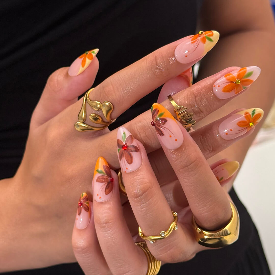 Autumn floral press on nails with hand-painted orange and red flowers, gem accents, and nude-to-warm gradient bases — custom made medium almond nails, reusable luxury nail art — perfect for fall, autumn looks, or romantic seasonal style.