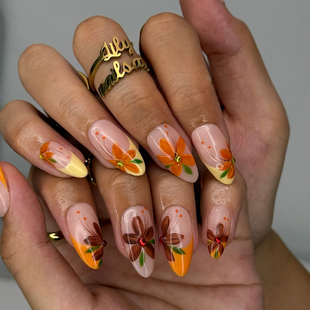 Autumn floral press on nails with hand-painted orange and red flowers, gem accents, and nude-to-warm gradient bases — custom made medium almond nails, reusable luxury nail art — perfect for fall, autumn looks, or romantic seasonal style.