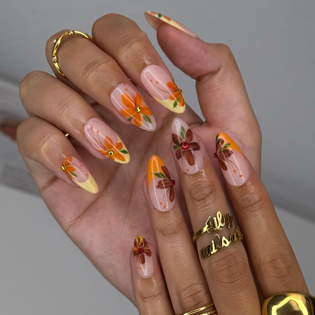 Autumn floral press on nails with hand-painted orange and red flowers, gem accents, and nude-to-warm gradient bases — custom made medium almond nails, reusable luxury nail art — perfect for fall, autumn looks, or romantic seasonal style.