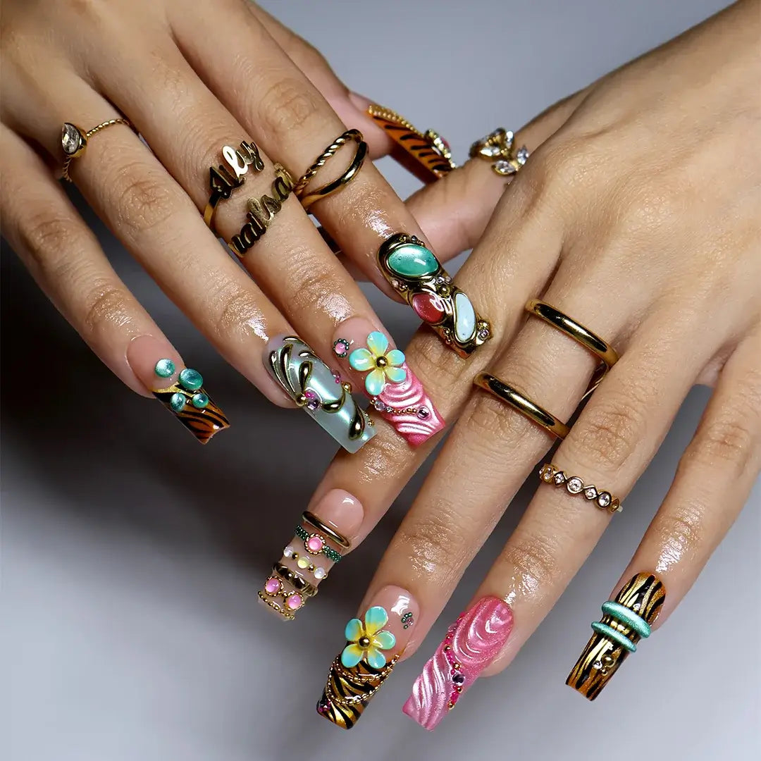 hand model wearing pink & tiffaniy handmade press-on nails — maximalist long square set with gold tiger print, cat-eye gems, 3D daisies and heart charm