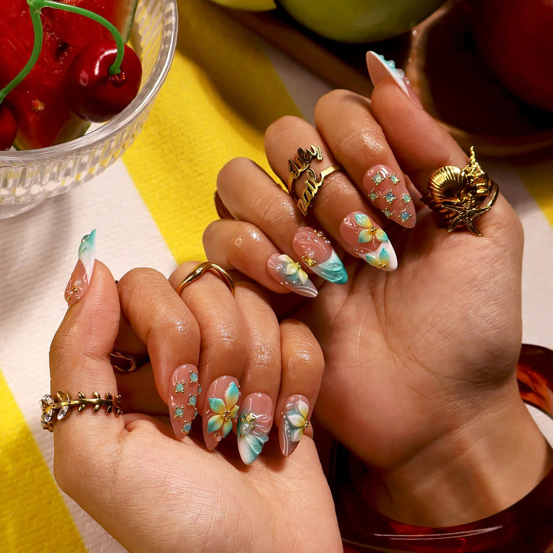 Handmade summer press-on nails with teal aqua tips, hand-painted tropical blooms and gold crystal embellishments by Lily Nails Art