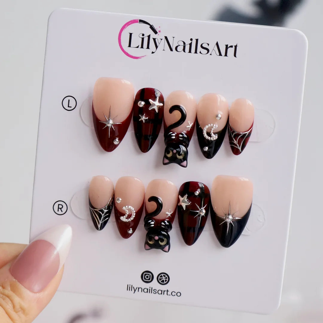 Meow gothic Halloween press on nails in nude, dark red and black with adorable 3D black cats, rhinestone moons, silver stars, spiderwebs and plaid accents — handmade designer press on nails, medium almond fake nails and cute witchy nail art.