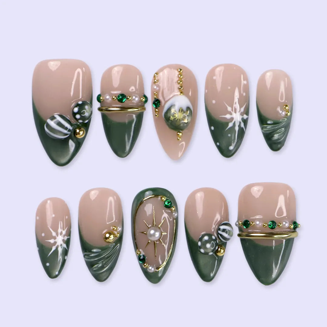 Emerald Eve handmade Christmas press-on nails — medium almond set in nude and sage-green cat-eye with 3D Christmas ornament baubles, gold starbursts, pearls, emerald gemstones and delicate snowflake accents.