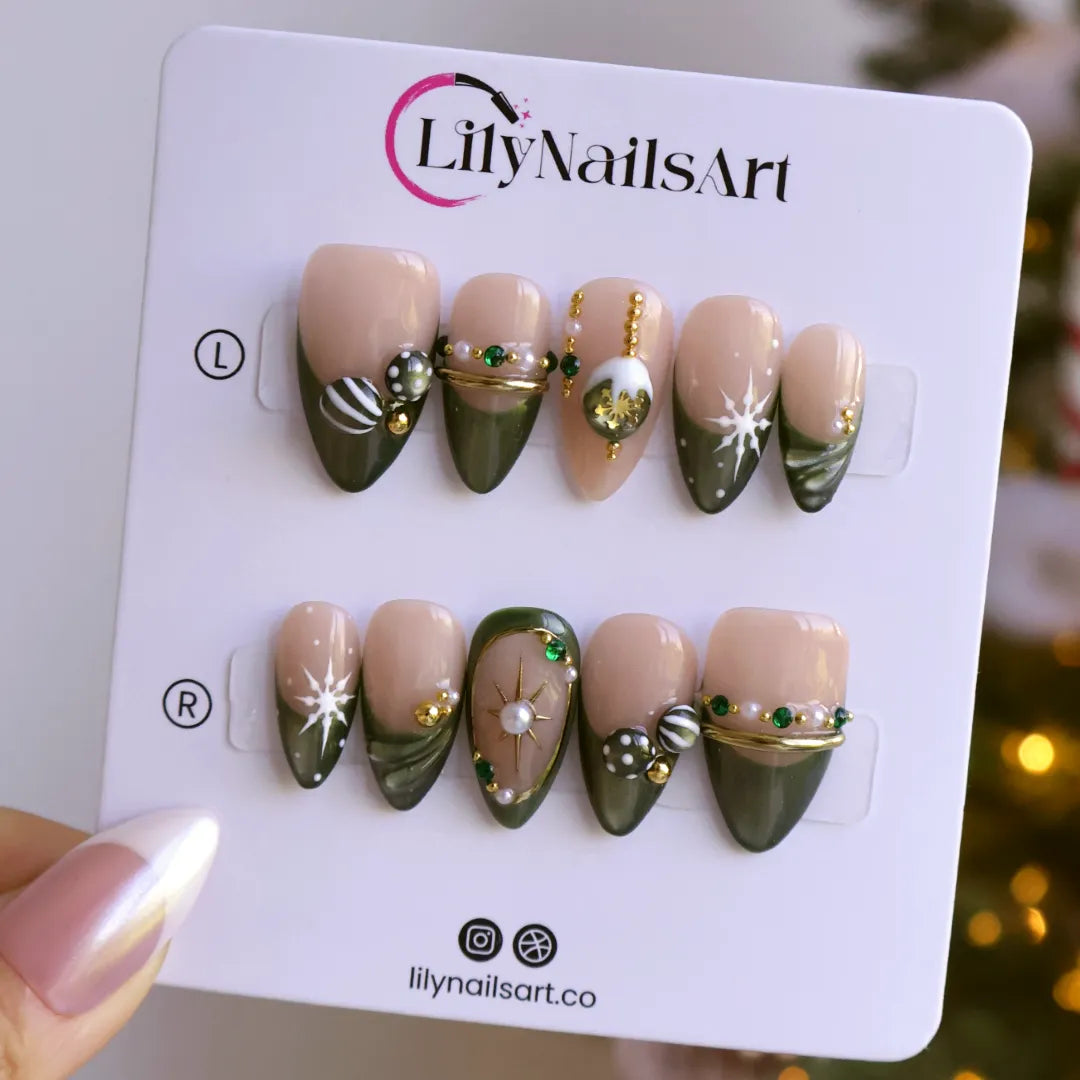 Emerald Eve handmade Christmas press-on nails — medium almond set in nude and sage-green cat-eye with 3D Christmas ornament baubles, gold starbursts, pearls, emerald gemstones and delicate snowflake accents.