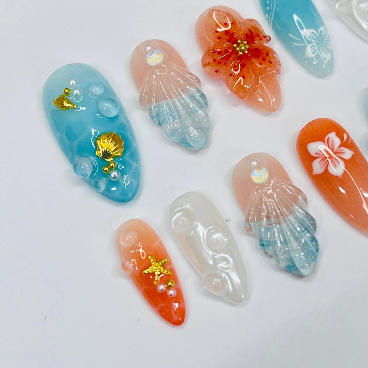 Handmade Tropical Ocean Press-On Nails – vibrant blue and coral tones with 3D seashells, flowers, starfish, and pearl accents. Perfect for summer holidays, birthdays, vacations, or as a unique gift for her.