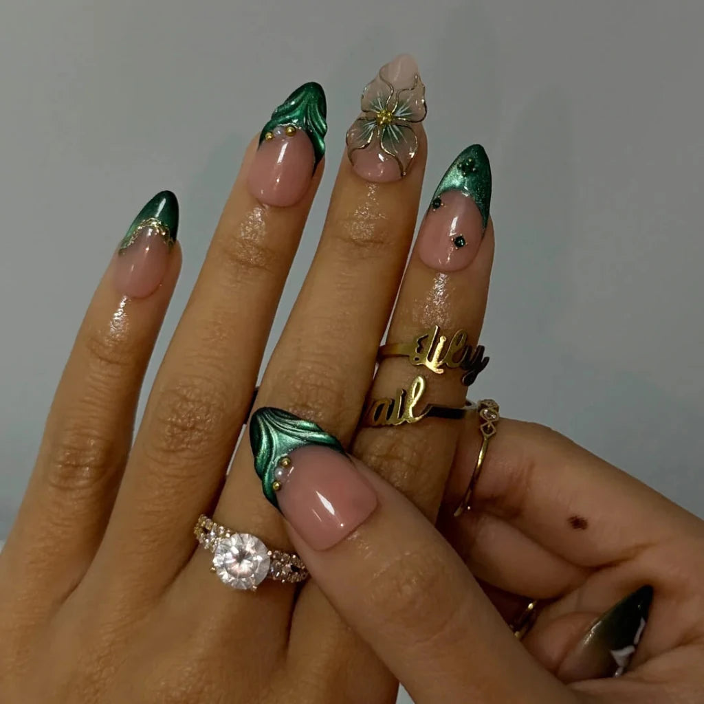 3D emerald green press on nails with white lily florals and gold vine accents, embellished with emerald crystals, pearls, and gold chain details on a nude base — custom press on nails, luxury handmade nail art, fake nails, false nails, pressons — perfect for prom, galas, and emerald-themed events