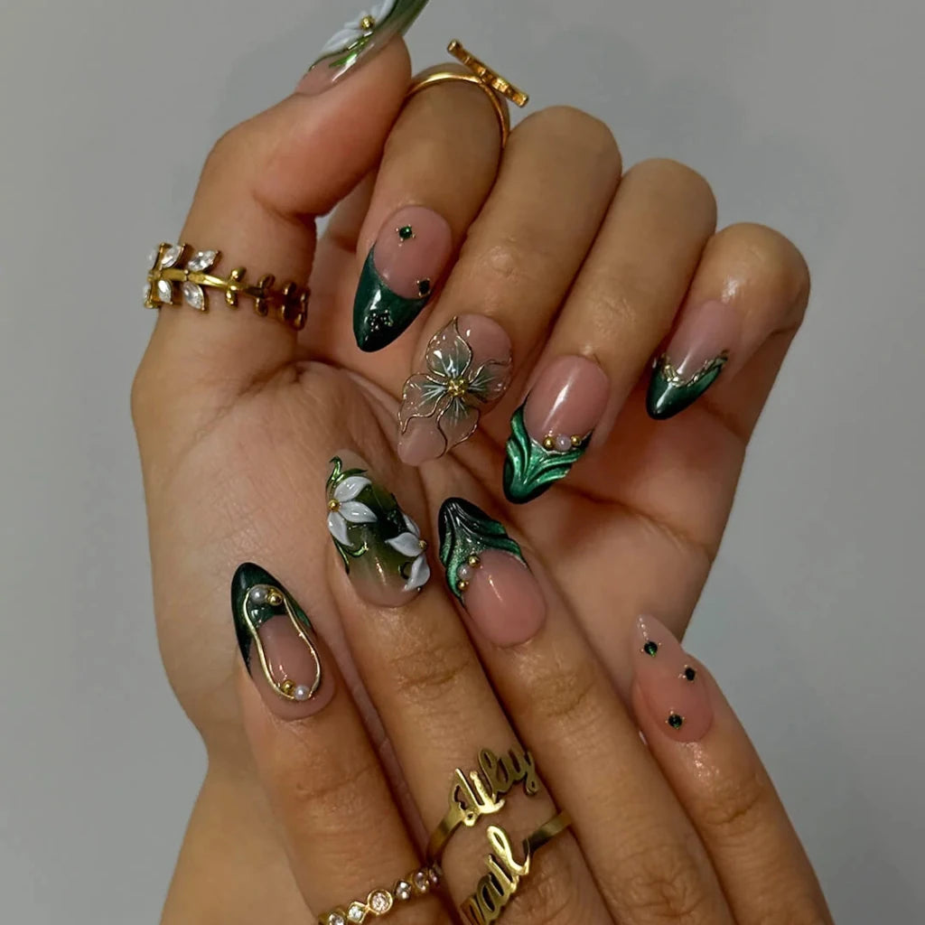 3D emerald green press on nails with white lily florals and gold vine accents, embellished with emerald crystals, pearls, and gold chain details on a nude base — custom press on nails, luxury handmade nail art, fake nails, false nails, pressons — perfect for prom, galas, and emerald-themed events
