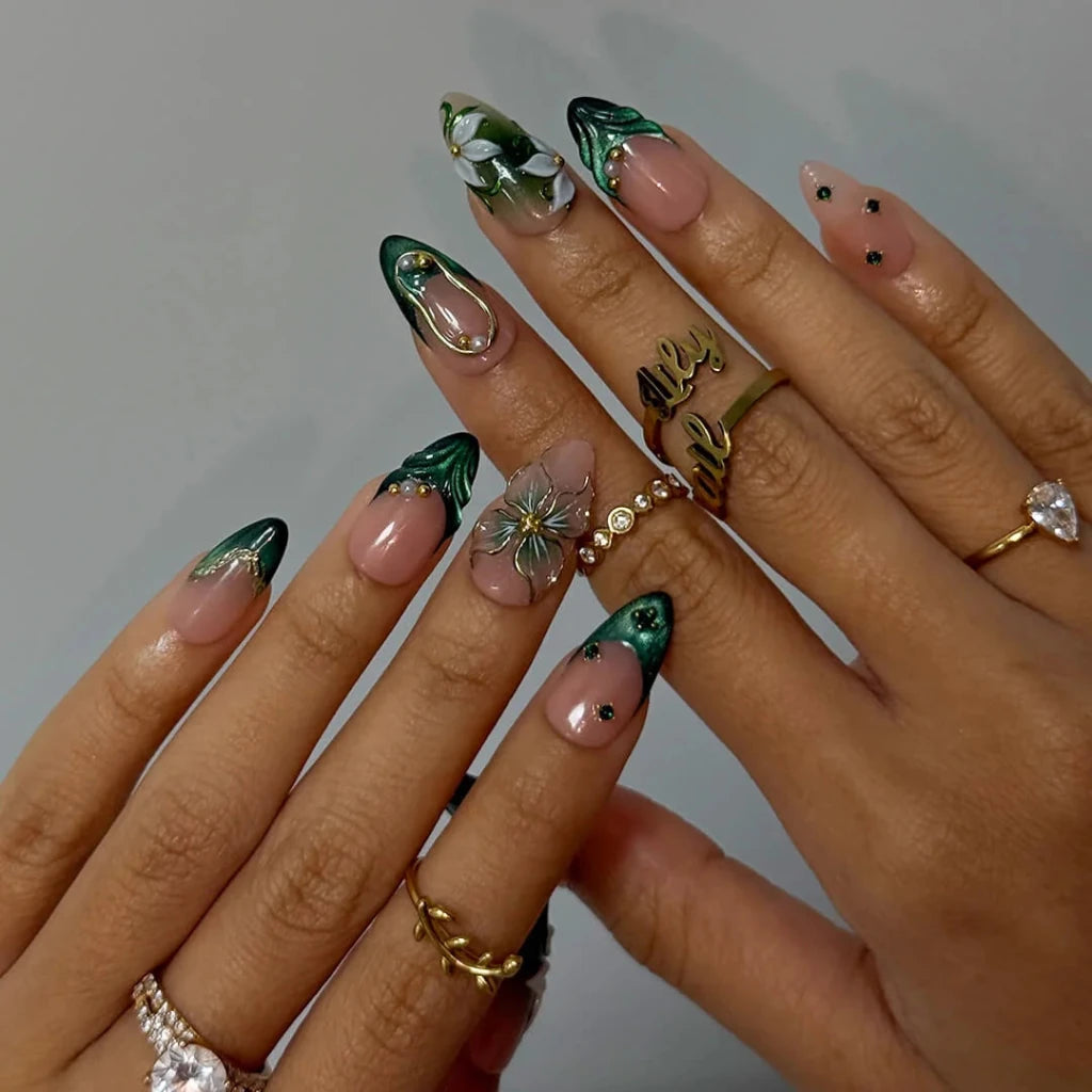 3D emerald green press on nails with white lily florals and gold vine accents, embellished with emerald crystals, pearls, and gold chain details on a nude base — custom press on nails, luxury handmade nail art, fake nails, false nails, pressons — perfect for prom, galas, and emerald-themed events