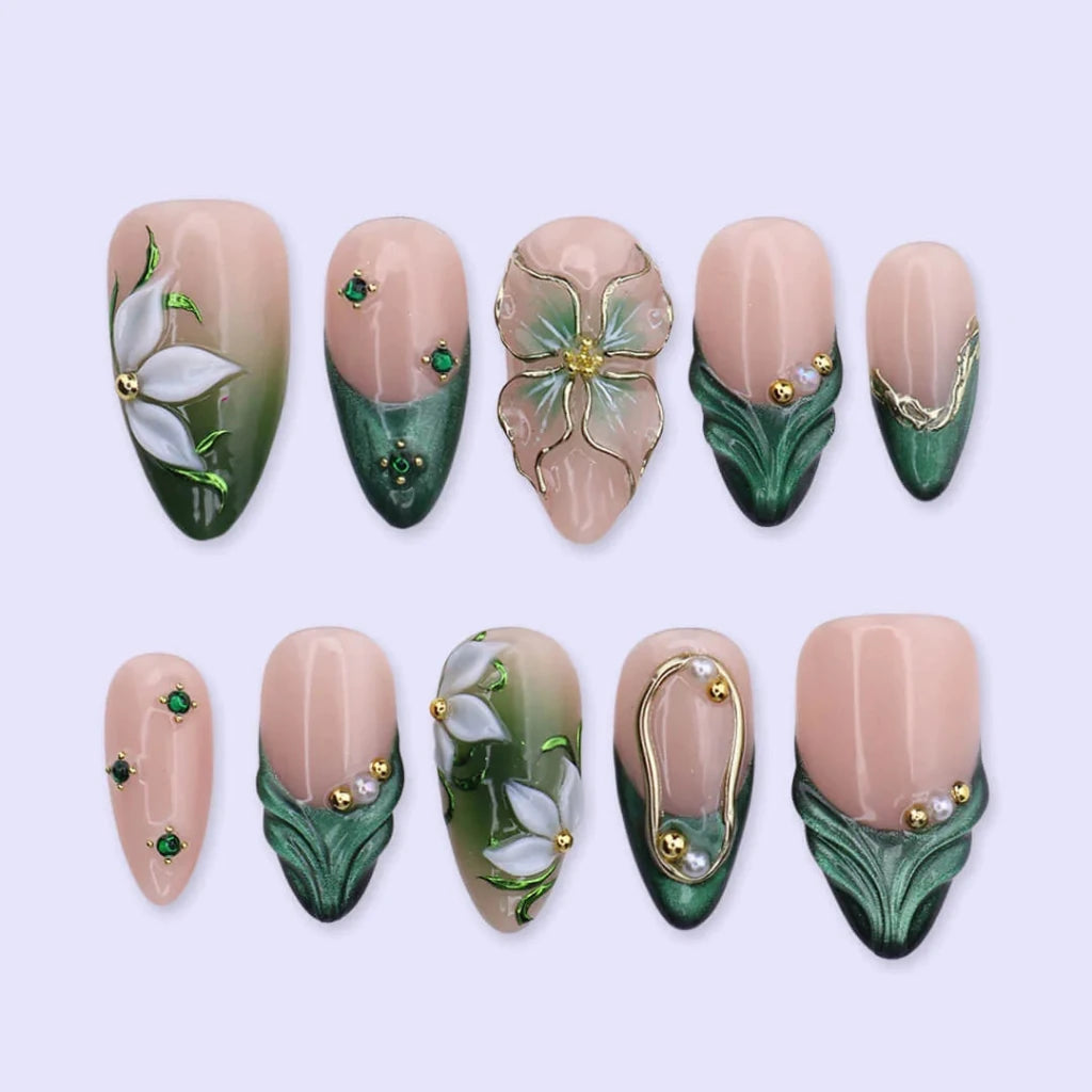 3D emerald green press on nails with white lily florals and gold vine accents, embellished with emerald crystals, pearls, and gold chain details on a nude base — custom press on nails, luxury handmade nail art, fake nails, false nails, pressons — perfect for prom, galas, and emerald-themed events