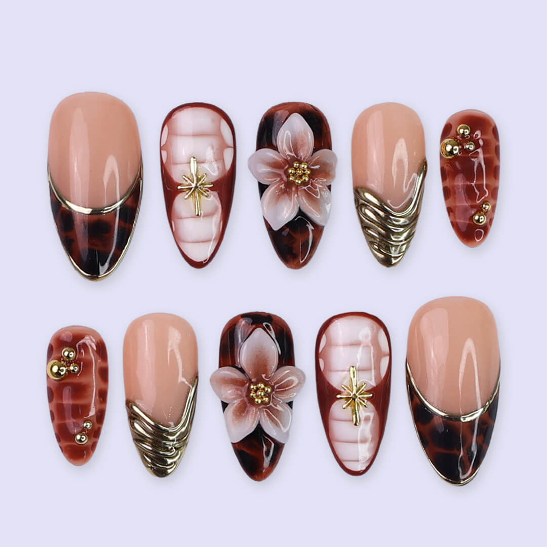 Luxury press-on nails with tortoiseshell patterns, 3D florals, and gold metallic accents on warm amber and nude bases — handmade medium almond nails — perfect for elegant everyday wear, chic autumn looks, or timeless luxury nail art.