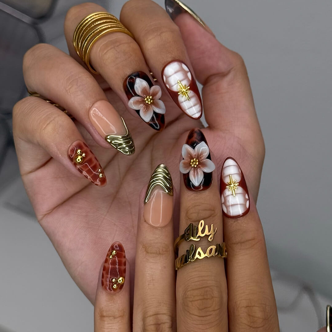Luxury press-on nails with tortoiseshell patterns, 3D florals, and gold metallic accents on warm amber and nude bases — handmade medium almond nails — perfect for elegant everyday wear, chic autumn looks, or timeless luxury nail art.