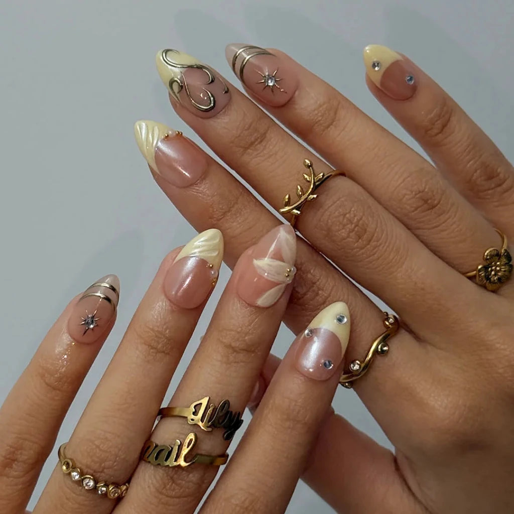 3D gold chrome French tip press on nails with swirl accents, embellished with starburst crystals and white floral details on a nude base — custom press on nails, luxury handmade nail art, fake nails, false nails, pressons — perfect for prom, weddings, and spring events