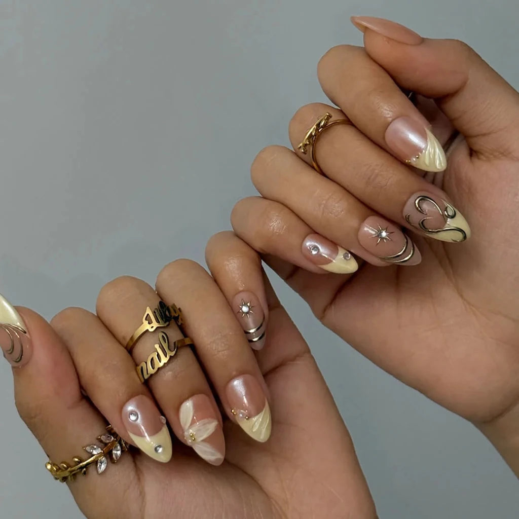 3D gold chrome French tip press on nails with swirl accents, embellished with starburst crystals and white floral details on a nude base — custom press on nails, luxury handmade nail art, fake nails, false nails, pressons — perfect for prom, weddings, and spring events