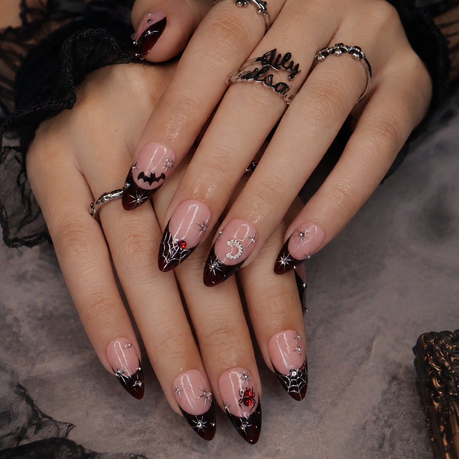Samhain handmade gothic Halloween press-on nails — medium almond set in nude with black French tips, silver starbursts, bat, jeweled spider, spiderwebs and crescent moon.