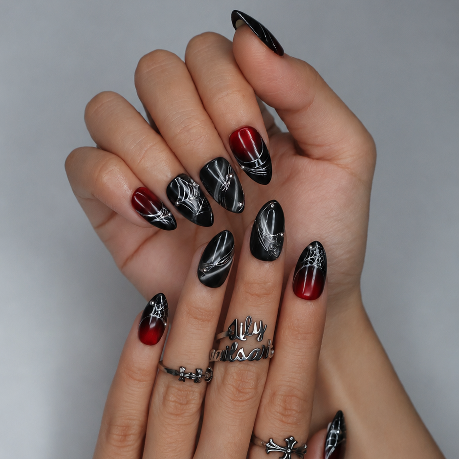 Arachne handmade gothic Halloween press-on nails — short almond set in blood-red and black cat-eye shimmer with silver spiderwebs and metallic bead accents.