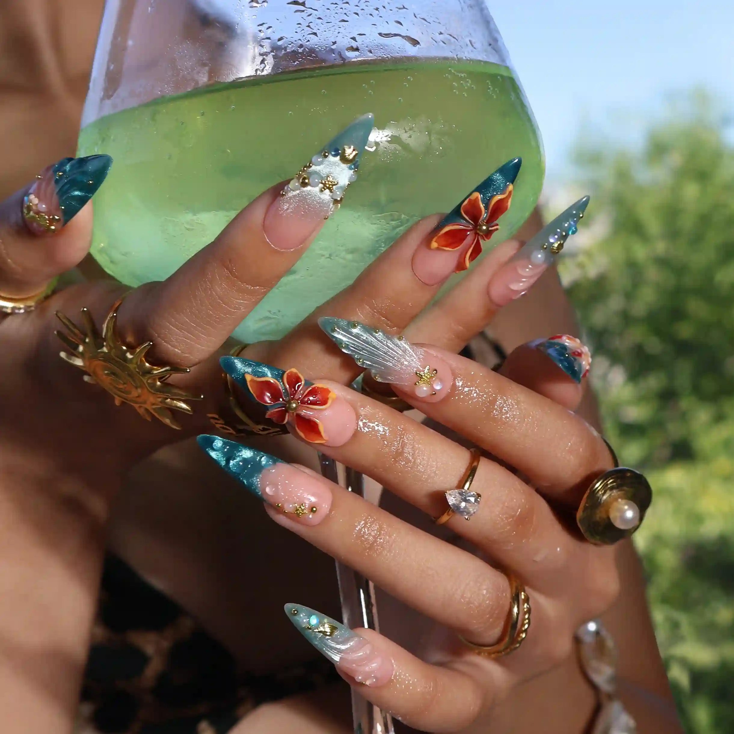 Handmade summer stiletto press-on nails with deep teal ocean base, amber bloom, starfish, gold seahorse charm and iridescent crystal embellishments by Lily Nails Art