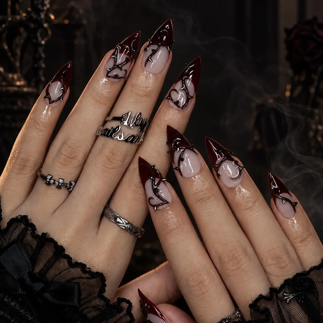 Forbidden gothic press on nails in nude and blood-red French tips with sculpted 3D thorny vines and silver spikes — handmade Halloween press on nails, long stiletto fake nails and gothic nail art.