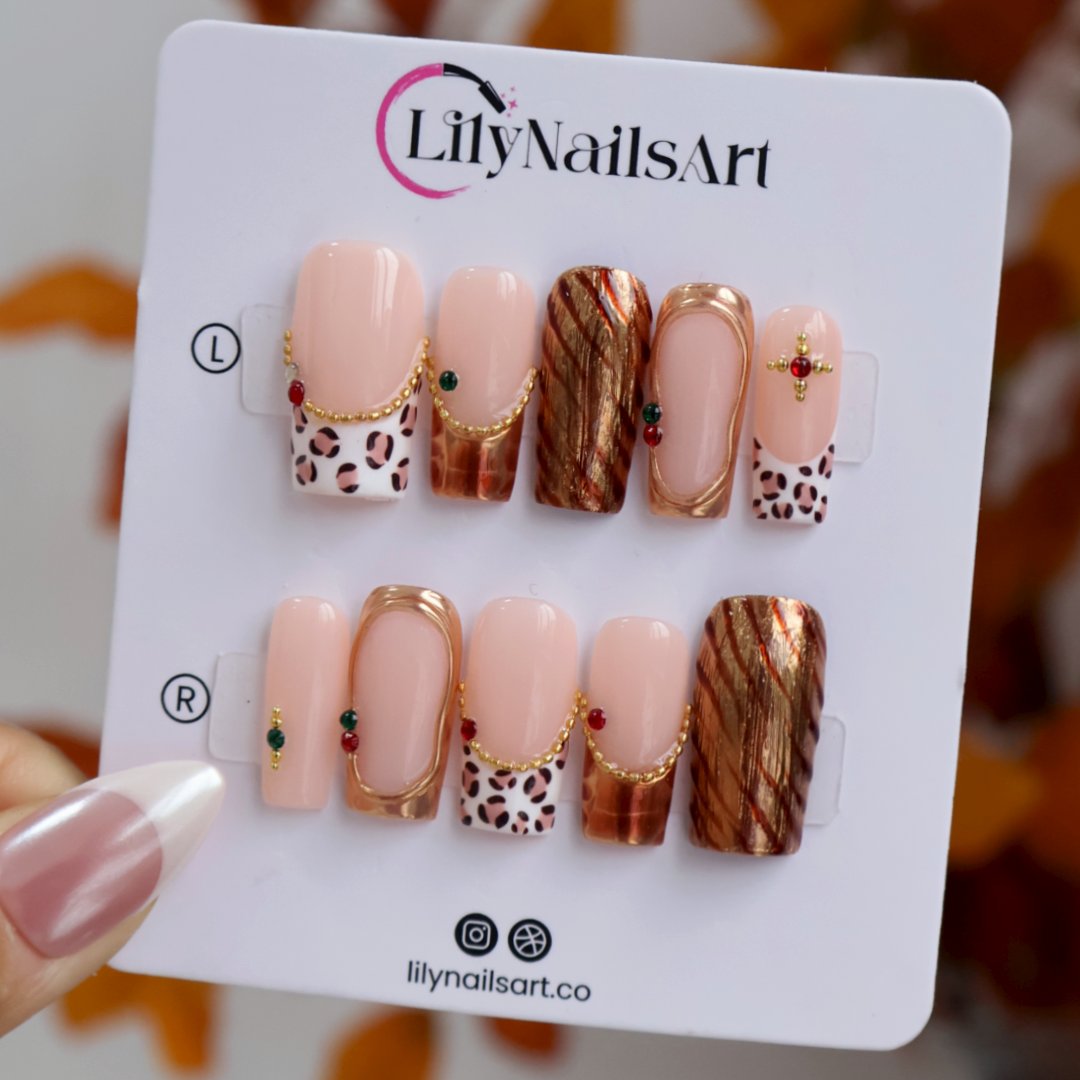 Moscato handmade fall press-on nails — medium square set in nude with leopard-print French tips, metallic gold tiger-stripe foil, gold mirror frame and red and green gemstone accents.