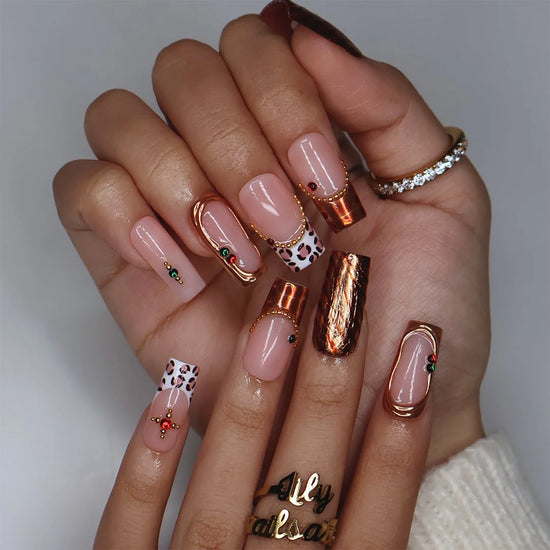 Moscato handmade fall press-on nails — medium square set in nude with leopard-print French tips, metallic gold tiger-stripe foil, gold mirror frame and red and green gemstone accents.