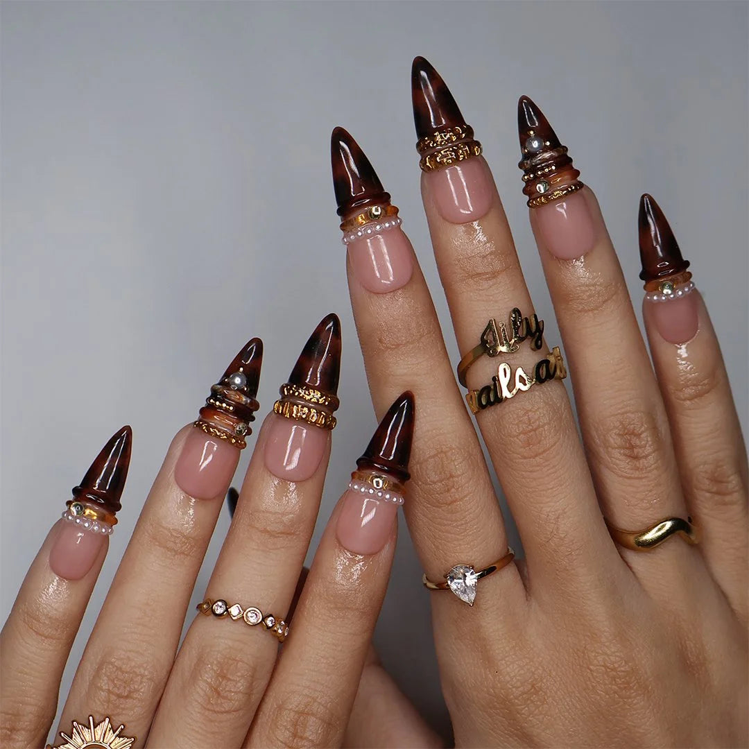 Bourbon handmade fall press-on nails — long almond set in nude fading into deep tortoiseshell brown with textured gold bands, delicate pearls and sparkling gemstone accents.