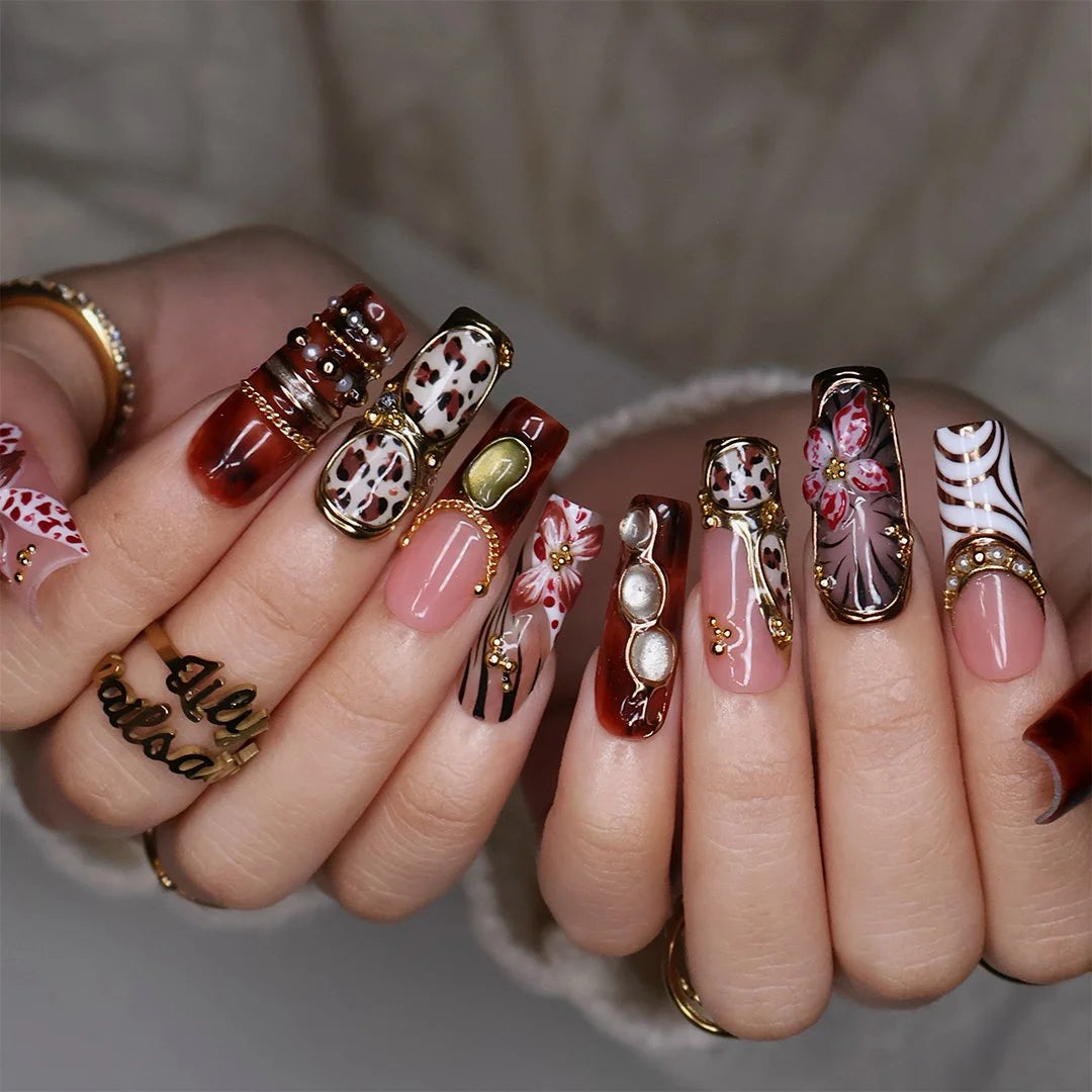 Zinfandel handmade fall press-on nails — maximalist long square set in nude, tortoiseshell and cream with 3D red-and-white orchids, olive and gold cat-eye cabochons, leopard and zebra prints, gold chains and pearl accents.