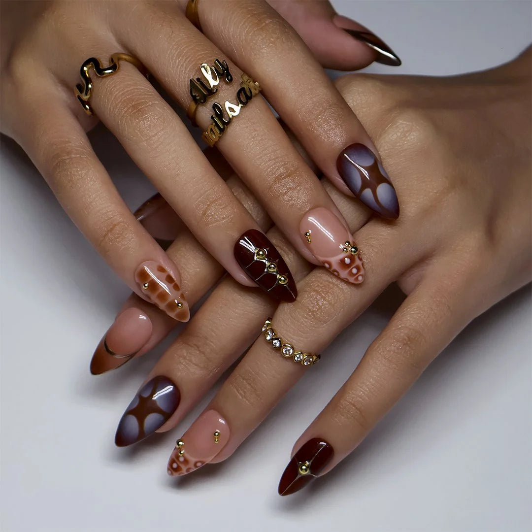Close-up of gold star charms and abstract cutout detail on brown almond nails