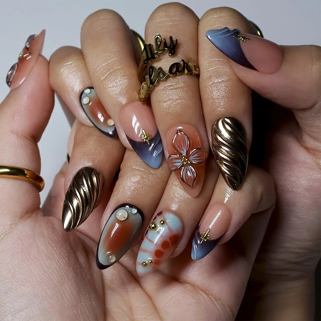 Close-up of sculpted liquid-gold waves and 3D lily detail on almond nails