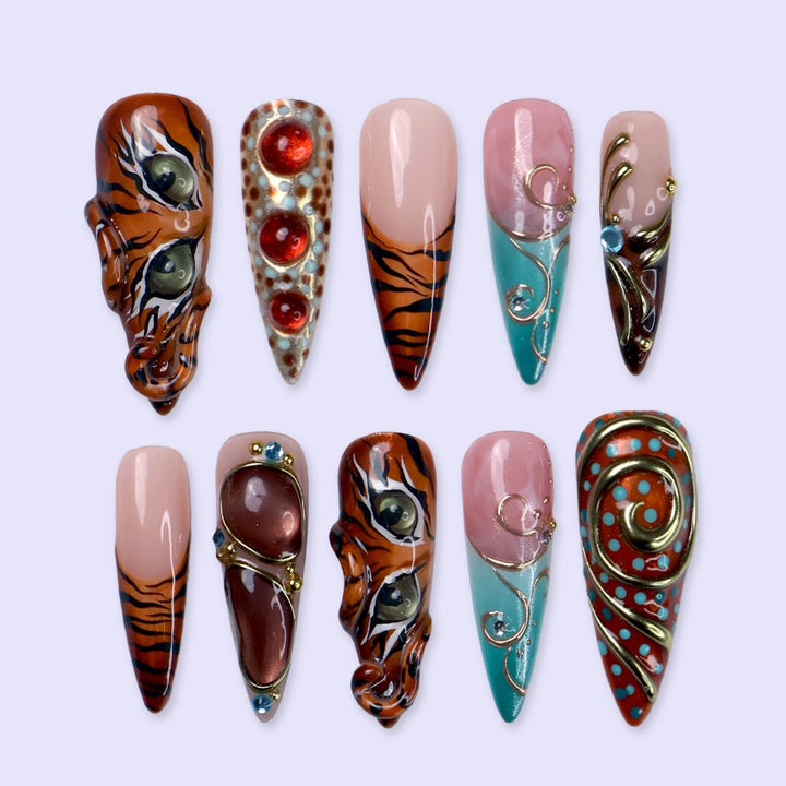 Handmade maximalist press on nail set with 3D tiger eyes, orange and black tiger stripes, turquoise and pink nails, gold swirls and red gems. Perfect for fall, birthday or party 