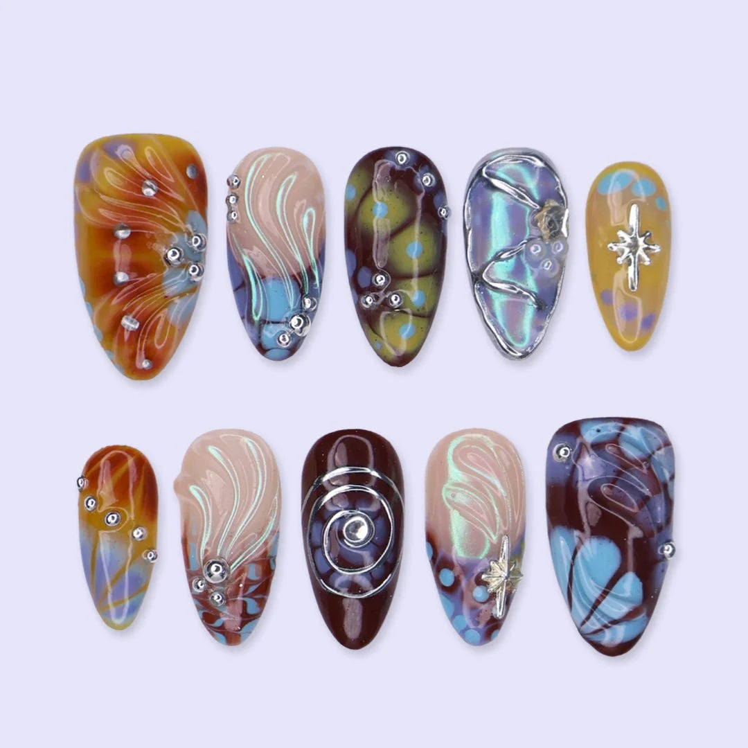 Asteria handmade Y2K press-on nails — almond set in caramel, brown and sky blue with silver chrome swirls, starbursts and marble effects
