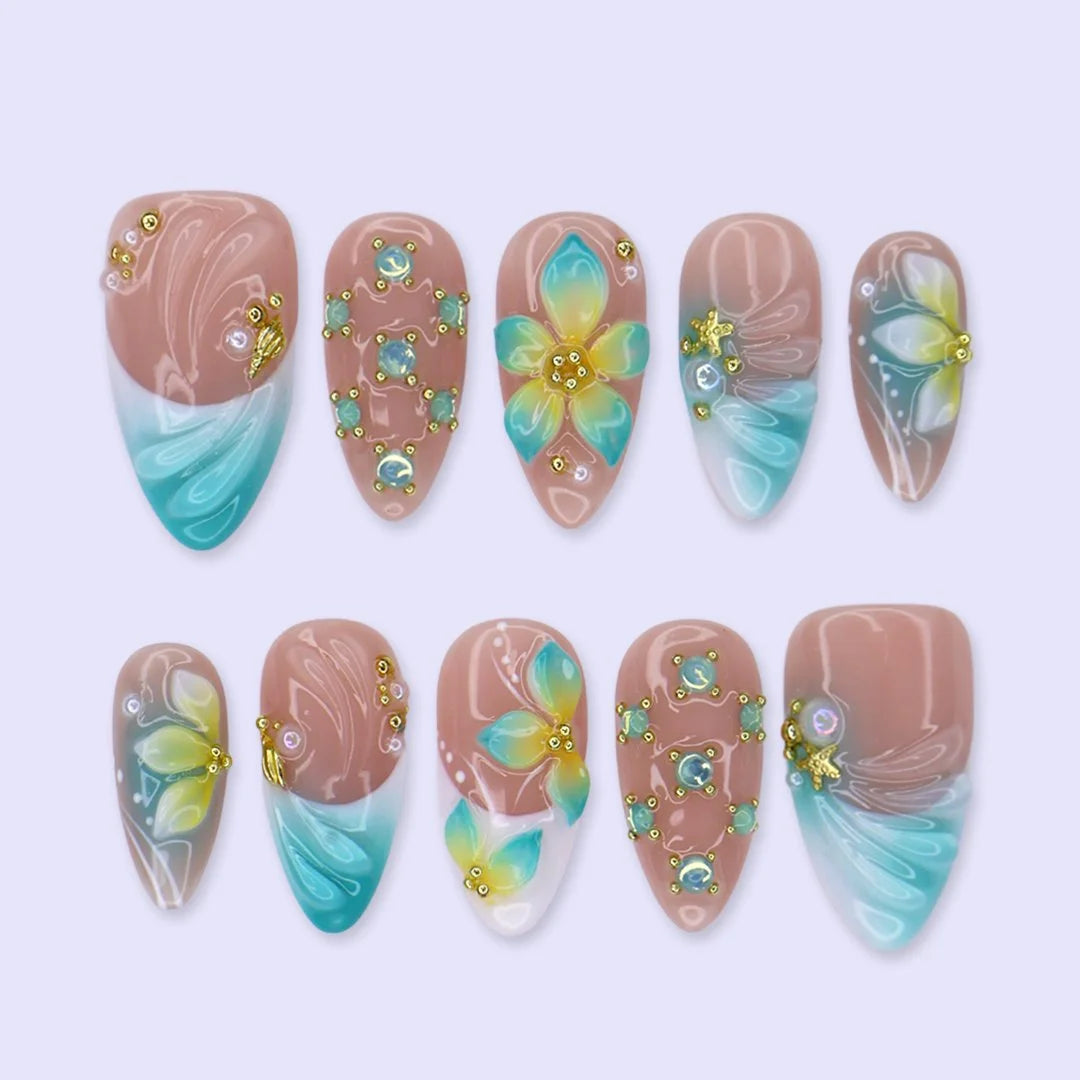 Handmade summer press-on nails with teal aqua tips, hand-painted tropical blooms and gold crystal embellishments by Lily Nails Art