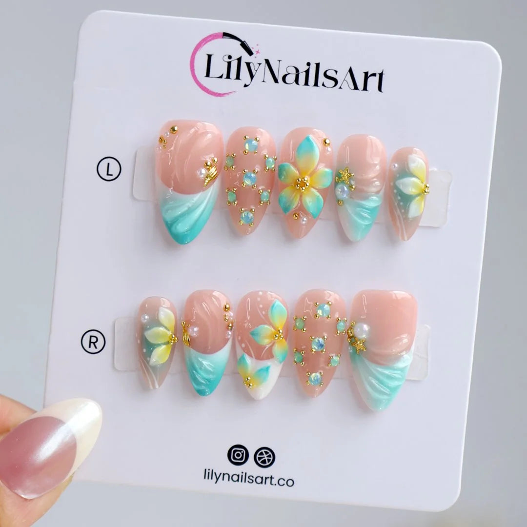 Handmade summer press-on nails with teal aqua tips, hand-painted tropical blooms and gold crystal embellishments by Lily Nails Art