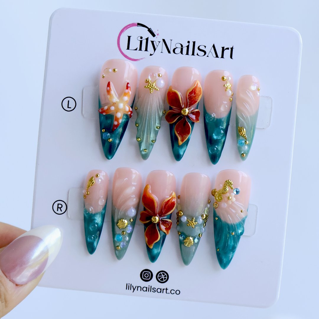 Handmade summer stiletto press-on nails with deep teal ocean base, amber bloom, starfish, gold seahorse charm and iridescent crystal embellishments by Lily Nails Art