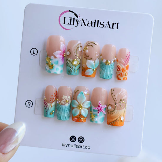 Handmade summer press-on nails with ocean art featuring seahorse, starfish, seashells, teal waves and gold swirl embellishments by Lily Nails Art