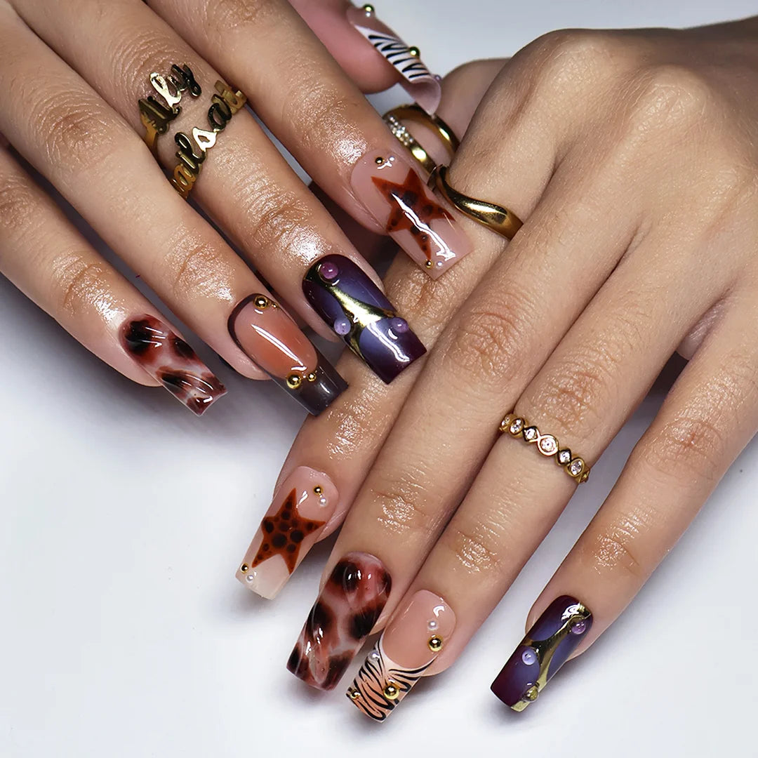 Stargazer handmade fall press-on nails — medium square set in nude, plum-purple and brown with tortoiseshell stars, gold accents and zebra-stripe tips
