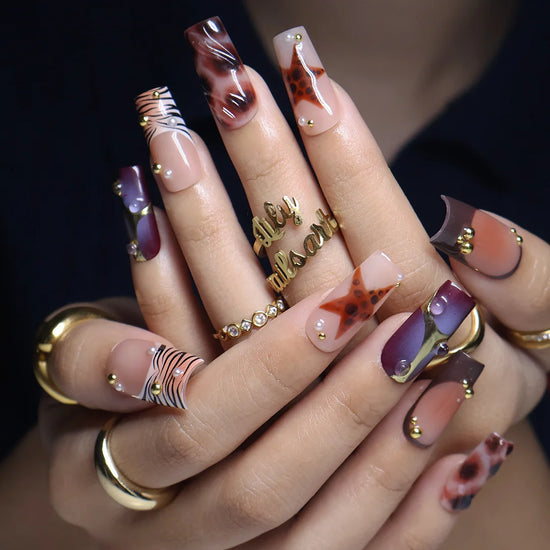 Stargazer handmade fall press-on nails — medium square set in nude, plum-purple and brown with tortoiseshell stars, gold accents and zebra-stripe tips