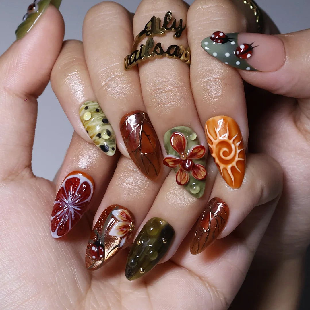Wildwood handmade fall press-on nails — almond set in olive green, rust and terracotta with 3D dragonfly, ladybugs, orchids and gold leaf-vein linework