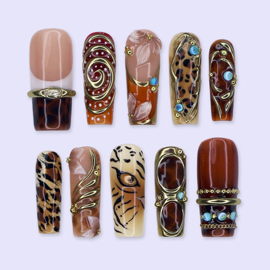 Safari handmade fall press-on nails — long square set in nude, caramel and amber with leopard, tiger print, gold swirls and gems