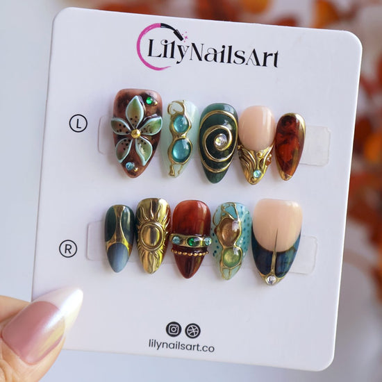 Solstice handmade maximalist press-on nails — almond set in teal, sage, rust and navy with a sculpted gold sun, 3D flower and jewel cabochons