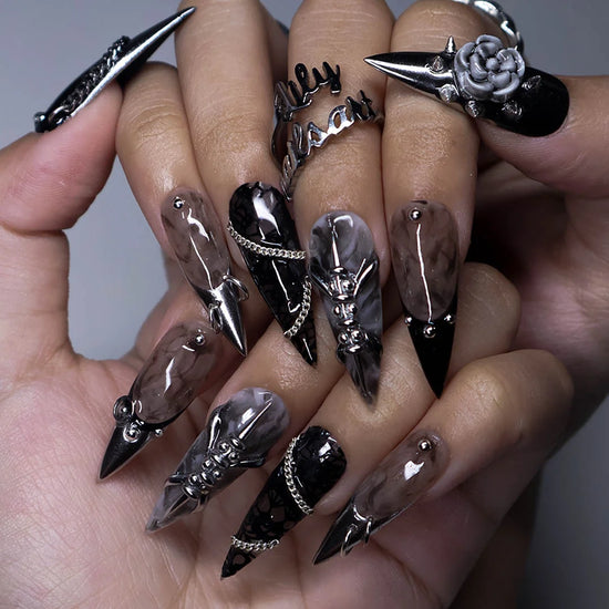 Vanquish gothic press on nails in black, smoky marble and taupe with chrome dagger tips, spikes, chains, black lace, metallic studs and a 3D grey rose — handmade Halloween press on nails, long stiletto fake nails and gothic nail art.
