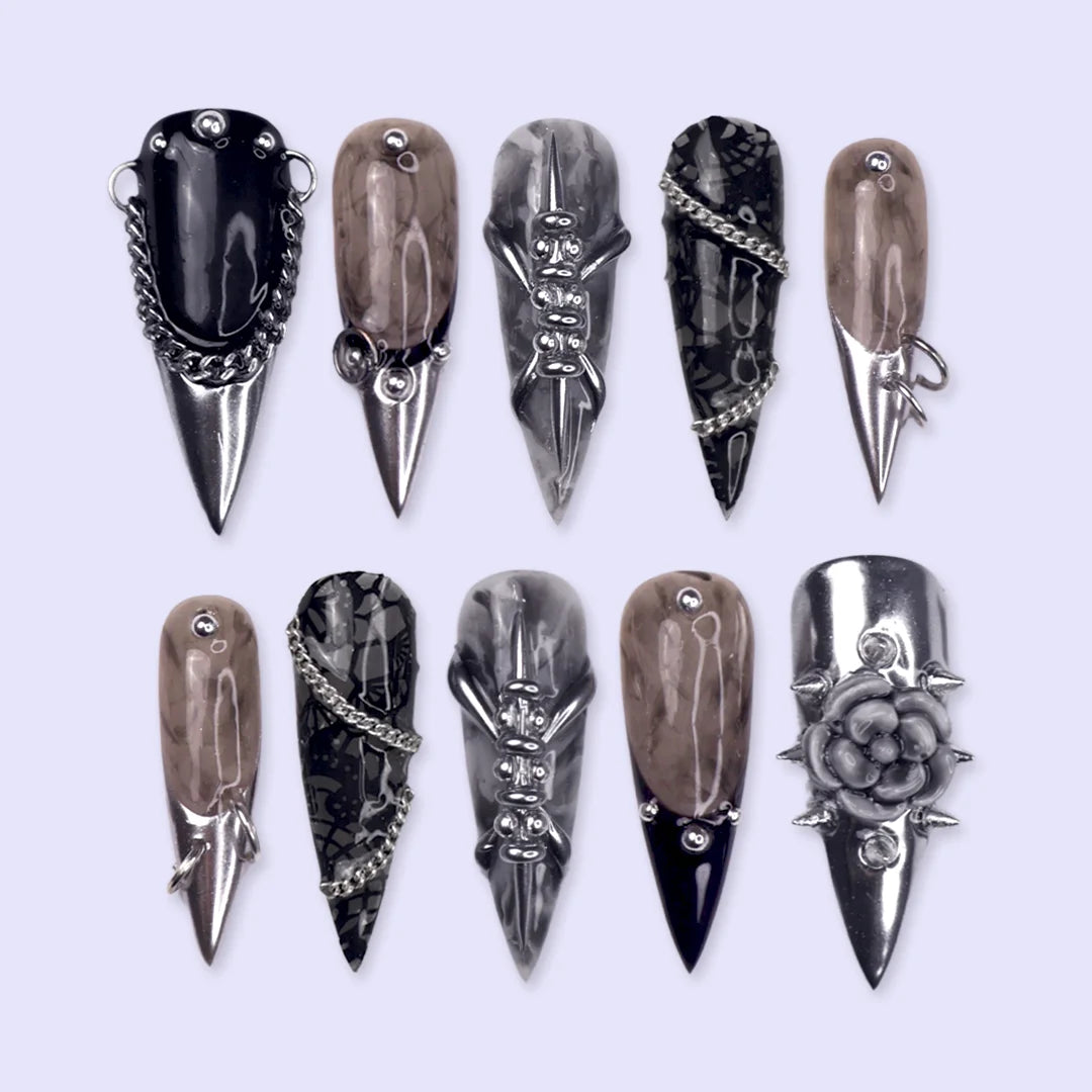 Vanquish gothic press on nails in black, smoky marble and taupe with chrome dagger tips, spikes, chains, black lace, metallic studs and a 3D grey rose — handmade Halloween press on nails, long stiletto fake nails and gothic nail art.
