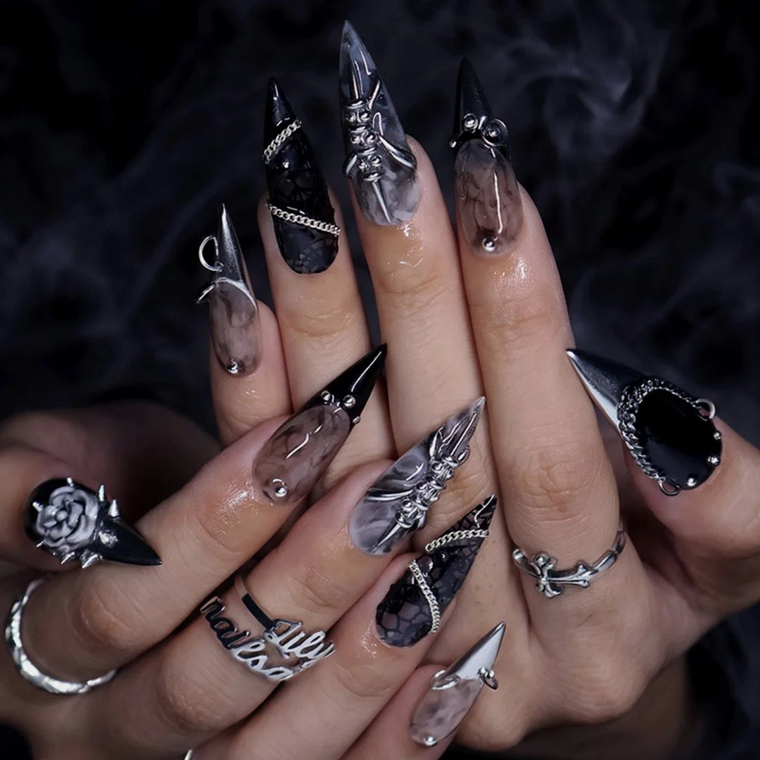 Vanquish gothic press on nails in black, smoky marble and taupe with chrome dagger tips, spikes, chains, black lace, metallic studs and a 3D grey rose — handmade Halloween press on nails, long stiletto fake nails and gothic nail art.