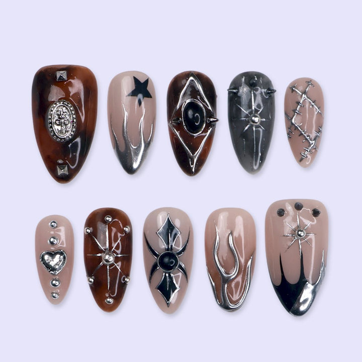 Séance gothic press on nails in nude, tortoiseshell brown and black with chrome silver flames, a 3D spider, ornate cameo, stars, heart charm and stitched details — handmade Halloween press on nails, medium almond fake nails and occult gothic nail art.