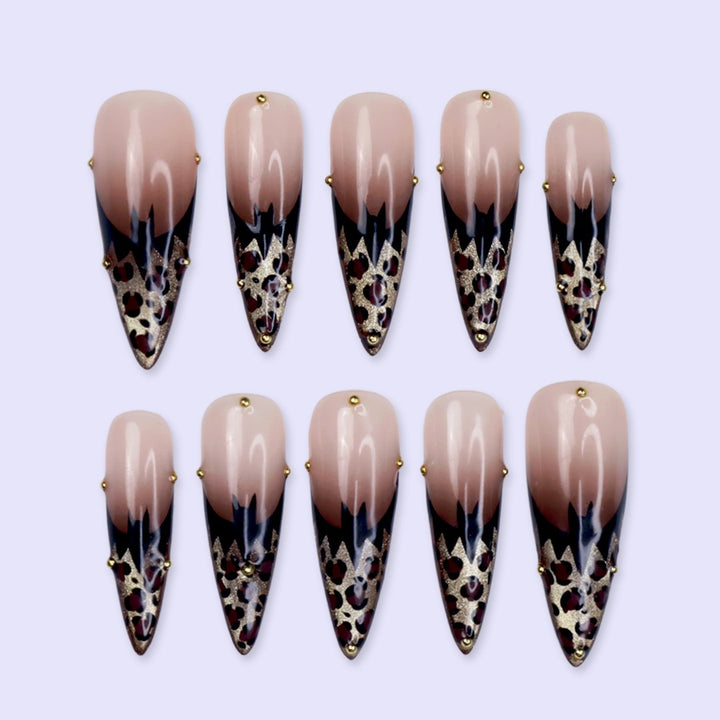 Prowl fall press on nails in nude with black and gold leopard-print French tips and delicate gold bead accents — handmade designer press on nails, long almond fake nails and animal print nail art.