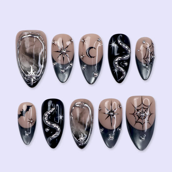 Eclipse gothic Halloween press on nails in nude, smoky black and silver chrome with a 3D snake, spiderwebs, bat, stars and crescent moon — handmade designer press on nails, medium almond fake nails and celestial witchy nail art.