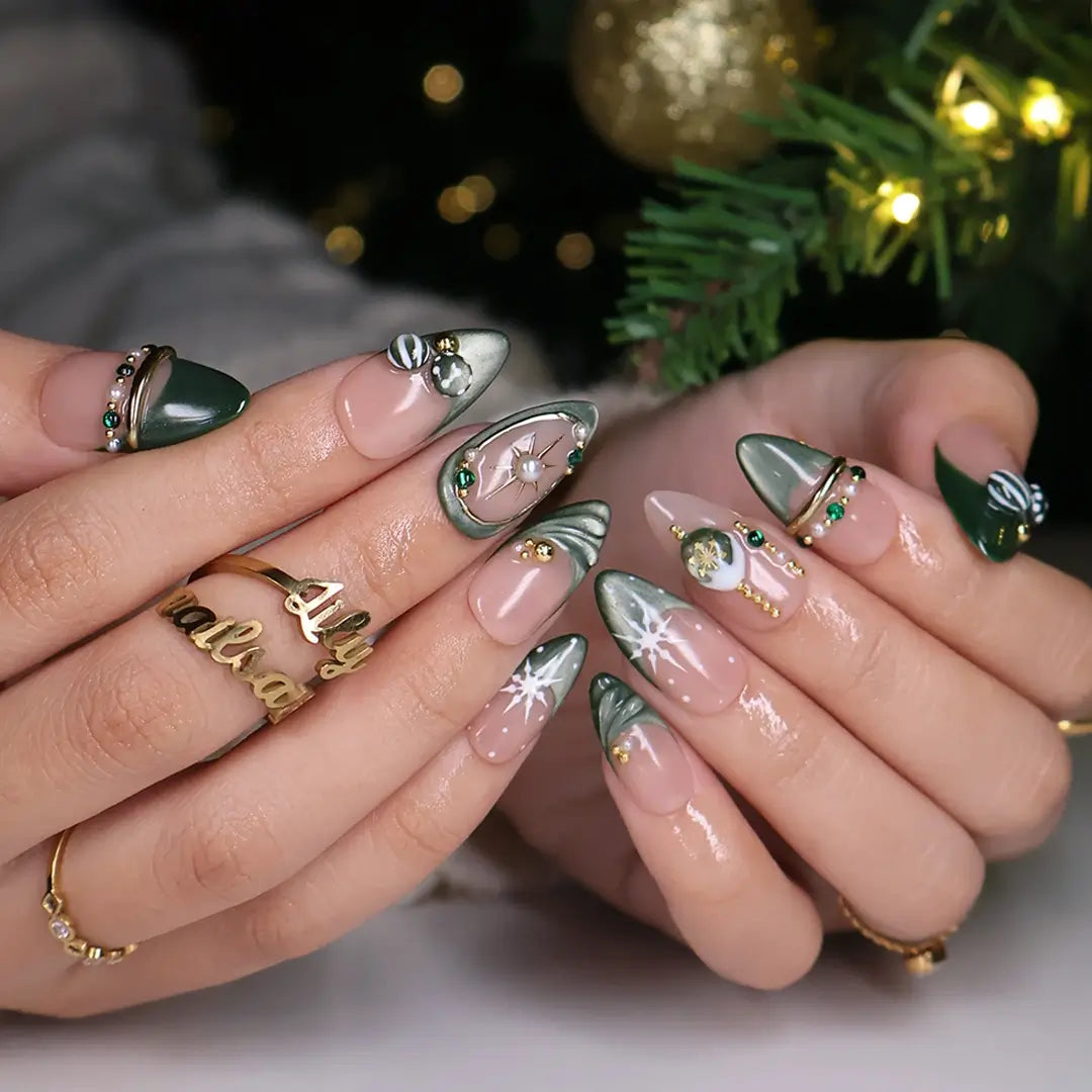 Emerald Eve handmade Christmas press-on nails — medium almond set in nude and sage-green cat-eye with 3D Christmas ornament baubles, gold starbursts, pearls, emerald gemstones and delicate snowflake accents.