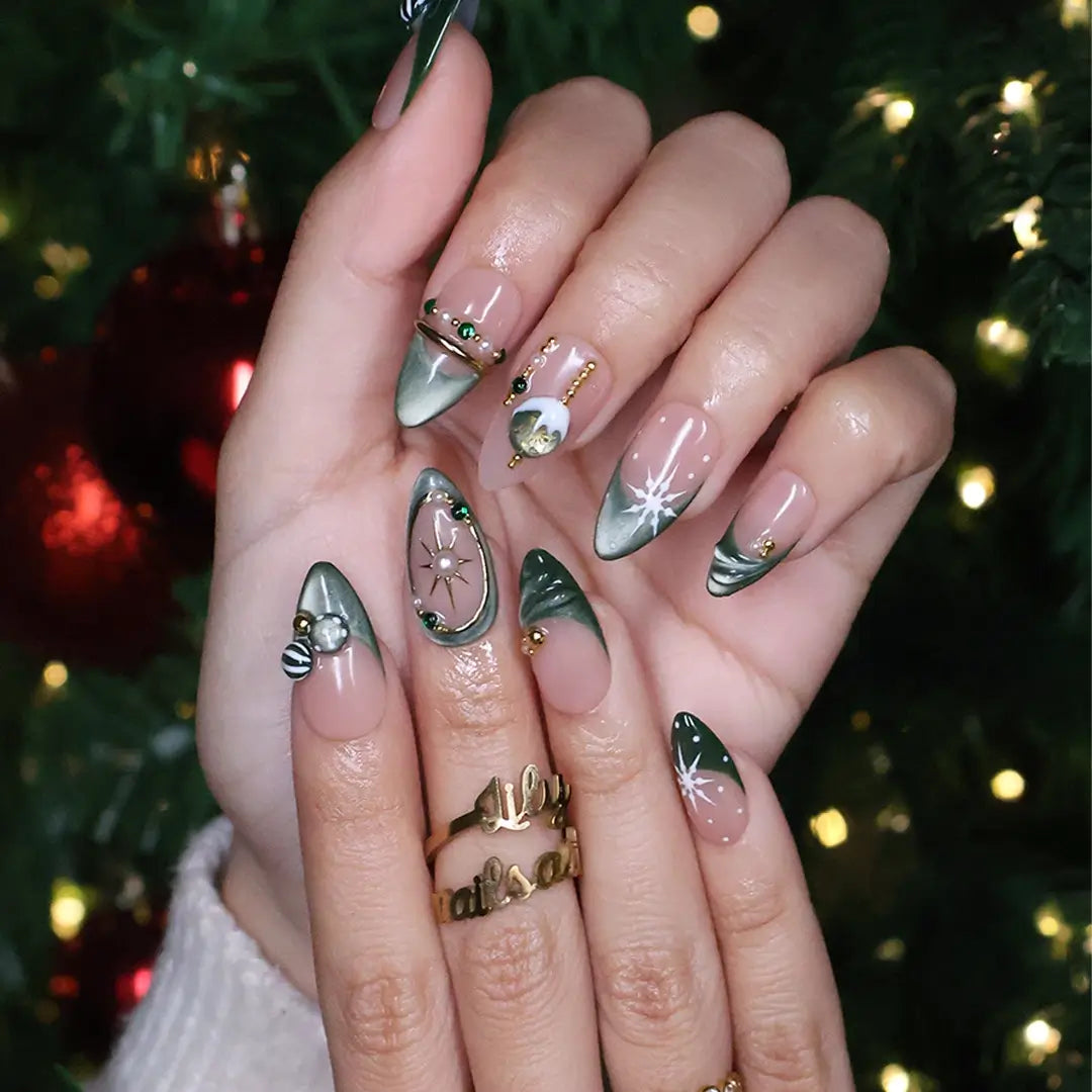 Emerald Eve handmade Christmas press-on nails — medium almond set in nude and sage-green cat-eye with 3D Christmas ornament baubles, gold starbursts, pearls, emerald gemstones and delicate snowflake accents.