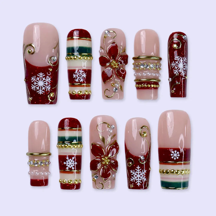 Poinsettia handmade Christmas press-on nails — long square set in nude and red glitter with 3D gold-outlined poinsettia flowers, white snowflakes, gold swirls, festive stripes and pearl accents.